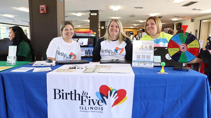 Three people at a Birth to Five Illinois Partnering for Early Learning table